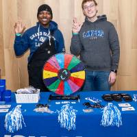 Two GV staff behind merch table giving Anchor Up sign